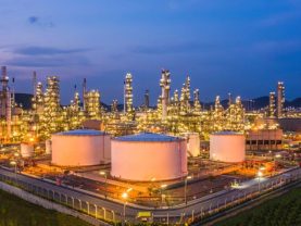 Oil refinery plant at night with storage tanks and processing towers